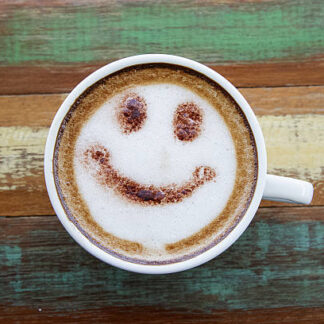 Smile face drawing on latte art coffee , wood color background