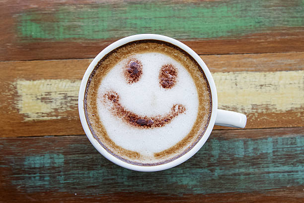 Smile face drawing on latte art coffee , wood color background