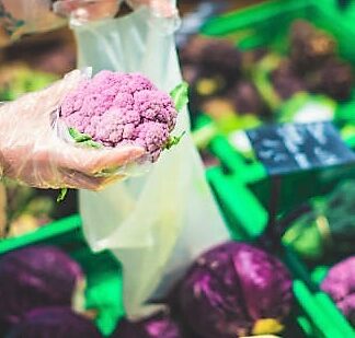 Picture of woman’s hands holding lilac cauliflower using biodegradable bag